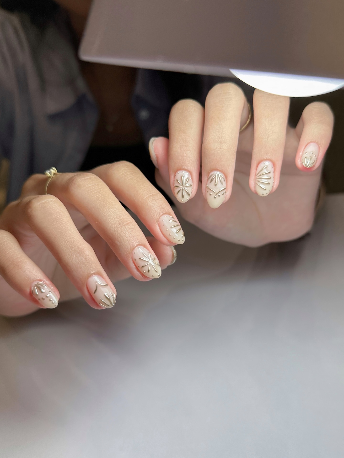 Sheer nude nails with embossed silver floral and starburst line art by Love, Luna
